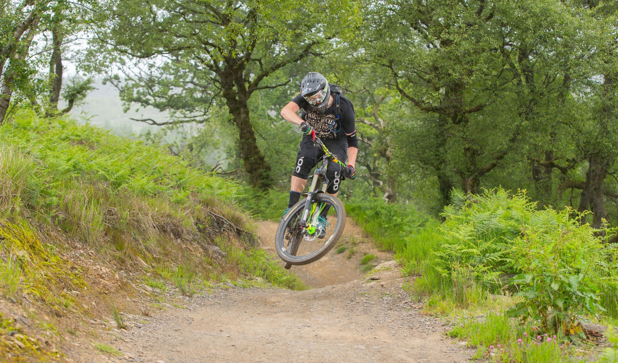 A mountain biker riding a wooded singletrack trail in Devon